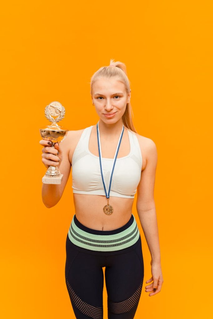Confident female athlete holding a trophy, symbolizing victory and success in sports.